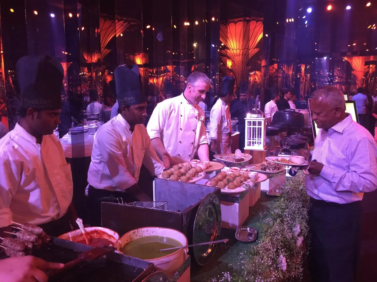 Chefs serving guests from a live counter at an evening celebration