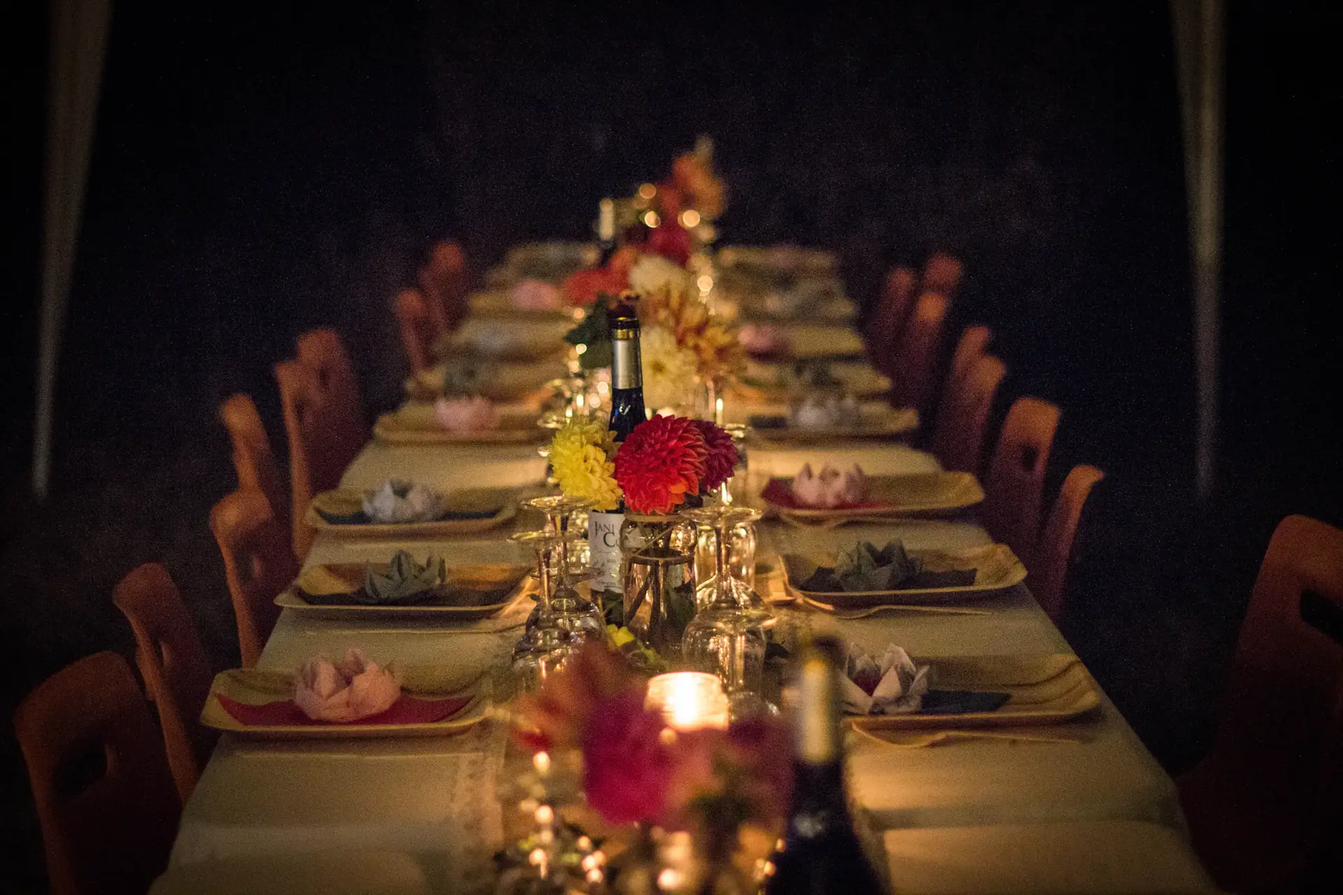 Long candlelit dinner table with flowers and glassware