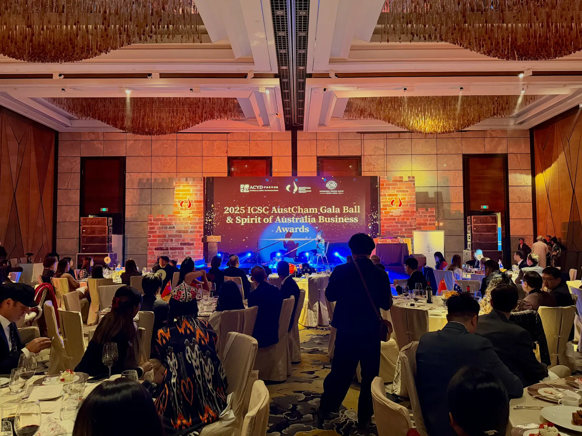 Guests seated at a corporate gala dinner facing a lit stage