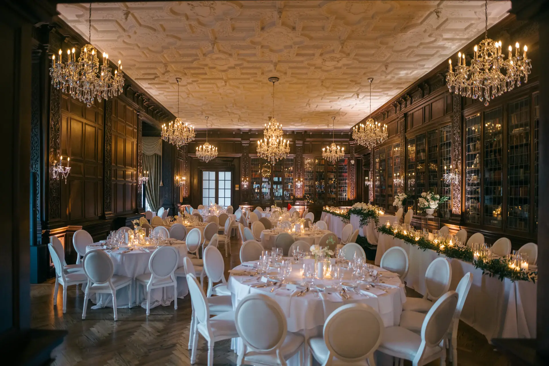 Wood-panelled ballroom with chandeliers and dressed dinner tables